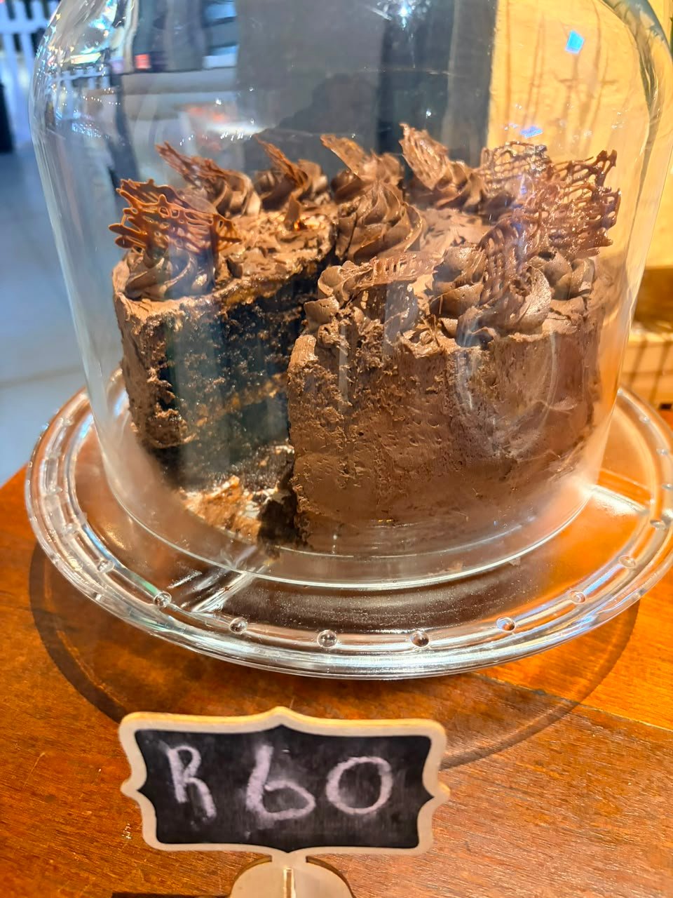 The chocolate cake under a glass dome on the counter